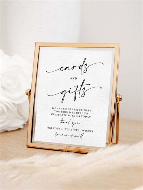 A White Card And Gift Sign Sitting On Top Of A Table Next To A Vase