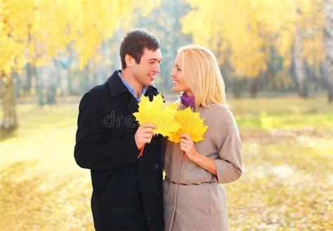 Portrait Of Happy Young Smiling Couple With Yellow Maple Leafs In Warm