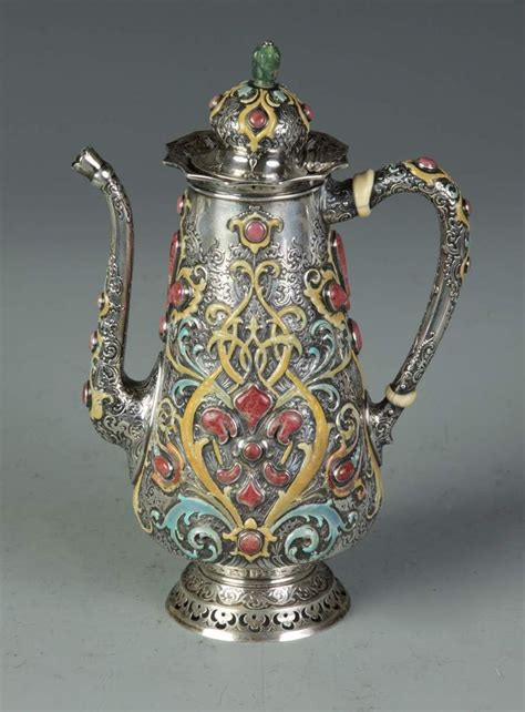 An Ornately Decorated Silver Teapot With Gold Trimmings And Red Blue