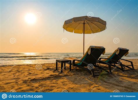 Sun Umbrellas And Chairs On Tropical Beach With Sunset Stock Image