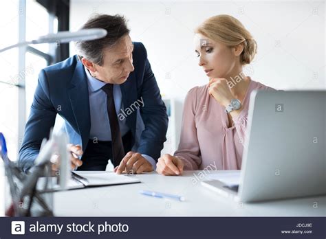 Mature Businessman And Businesswoman With Laptop And Documents Working In Office Stock Photo Alamy