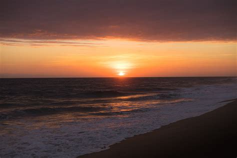 A sunset over the ocean with waves crashing · Free Stock Photo