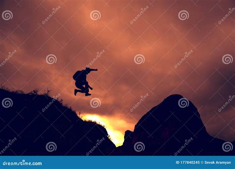 Man Silhouette Jump Happy From Cliff Over Gap Sunset Stock Image