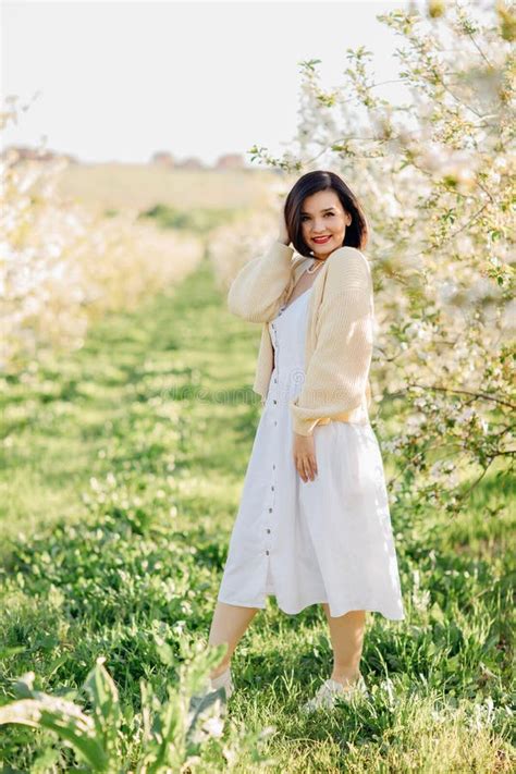 An Attractive Brunette In A White Dress In A Blooming Spring Garden Solar Glare Stock Image