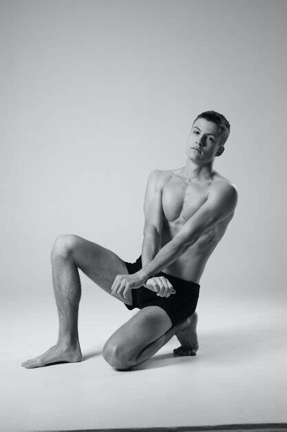 Premium Photo Athlete Sitting On The Floor Indoors In Shorts And Naked Torso Black And White