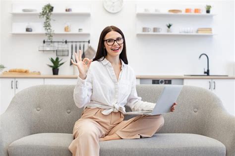 Una feliz mujer de negocios morena sentada en un cómodo sofá y usando