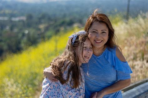 Madre E Hija De Latina Que Sonr En Y Que R En En Una Colina Delante De Las Flores Amarillas
