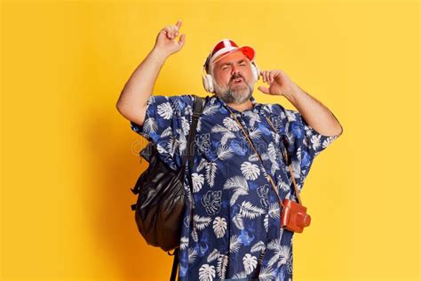 Portrait Of Fat Mature Man In Stylish Shirt Listening To Music In Headphones Posing Over