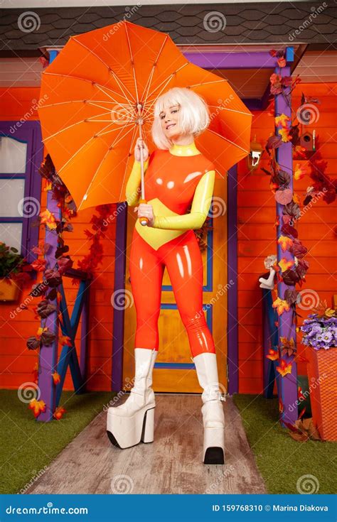 Hot Pretty Blonde Woman In Bright Colorful Latex Rubber Catsuit Ready For Halloween Autumn Party