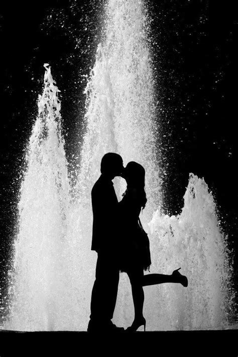 A Man And Woman Kissing In Front Of A Fountain