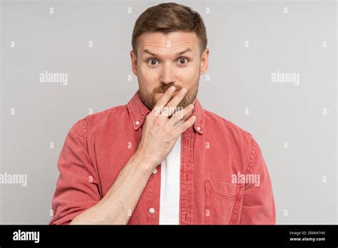 Amazed Confused Man With Raised Eyebrows Covering Mouth With Hand