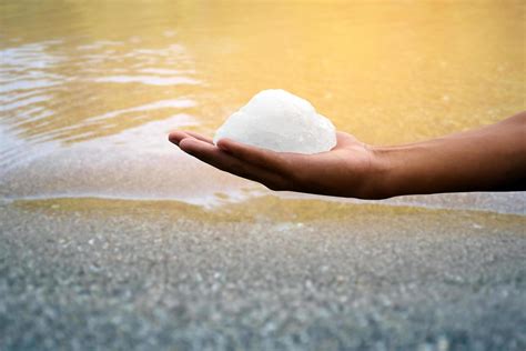 Barra De Alumbre Blanca Sosteniendo En La Mano Con Agua Turbia