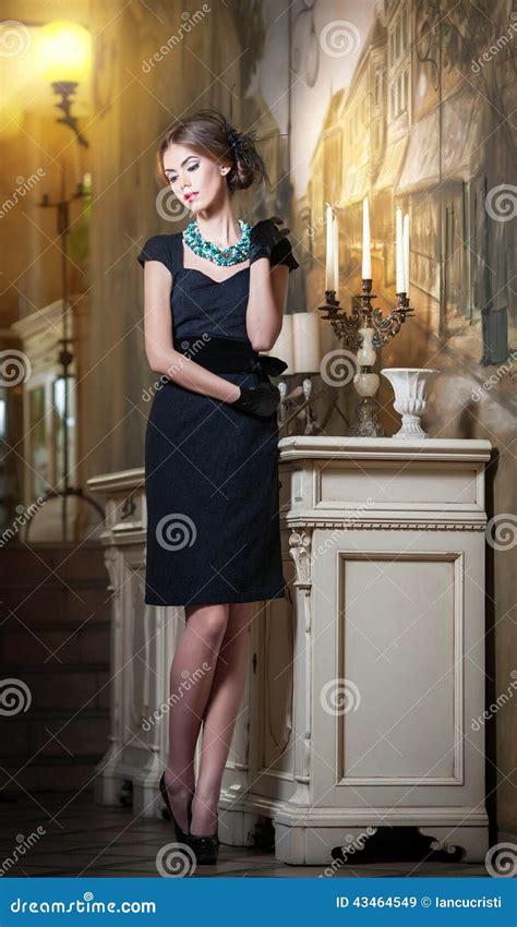 Young Beautiful Brunette Woman In Elegant Black Dress Standing Near A