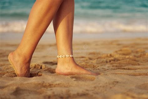 Tanned Legs Of A Woman On A Tropical Sandy Beach With Blurry Waves In