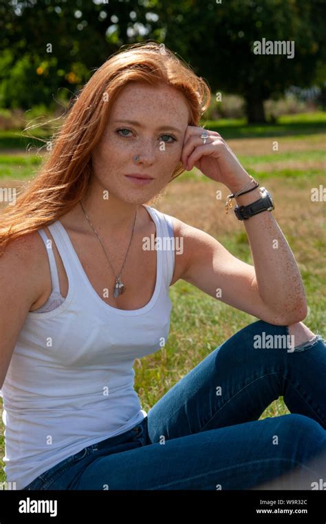 Tennage Girl Red Hair Freckles Sits On Grass Relaxed Look To Camera