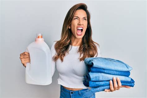 Jovem Latina Segurando Jeans Para Lavar Roupa E Detergente Garrafa Zangada E Louca Gritando