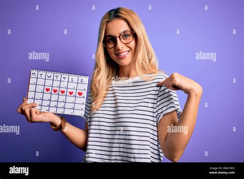 Jeune femme blonde jeune tenant calendrier de période pour contrôler le cycle menstruel avec le