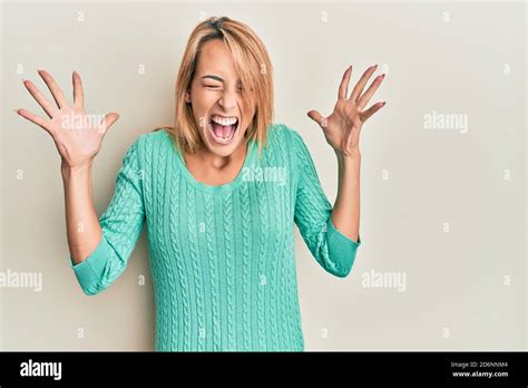 Belle femme blonde portant un chandail d hiver décontracté célébrant fou et fou pour le succès