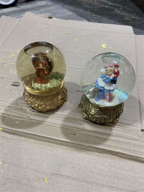 Two Snow Globes Sitting On Top Of A Table