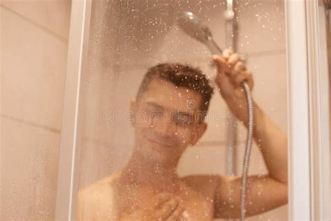 Happy Smiling Satisfied Man Posing Naked In The Shower Behind Glass With Drops Taking Shower In