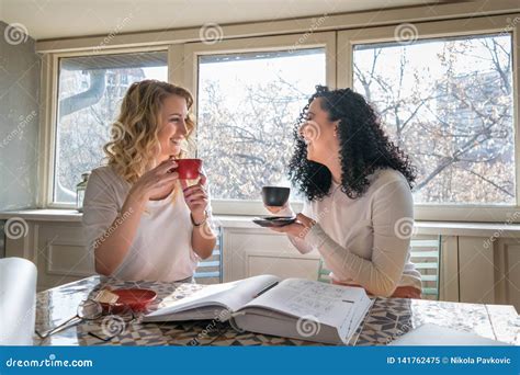 Two Girls Are Drinking Coffee And Laughing In Cafe Stock Image Image