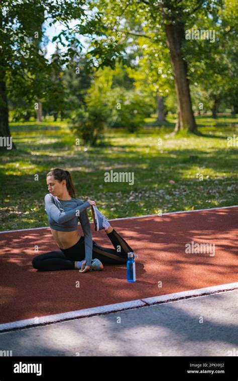 Fityoung Girl Stretching Out Her Leg Muscles On The Ground At The Park