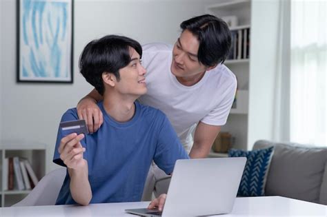 Jovem casal gay asiático segurando cartão de crédito e usando computador portátil empresário gay