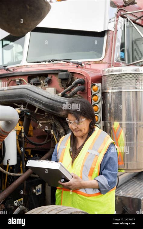 Female Mechanic With Clipboard Examining Semi Truck Engine Stock Photo