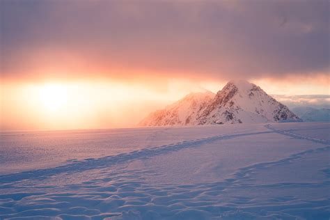 Snow Covered Mountain And Ground With Trail Tracks Under Cloudy Sky Hd