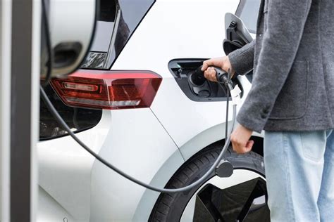 Hombre irreconocible conectando el cable de alimentación a un coche