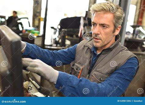 Mechanical Worker Setting Up Machines In Car Workshop Stock Photo