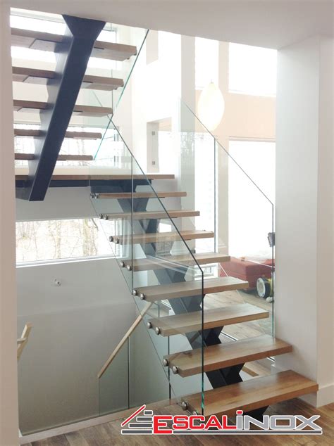 A Stair Case With Glass Railing And Wood Handrails In A Modern Style Home