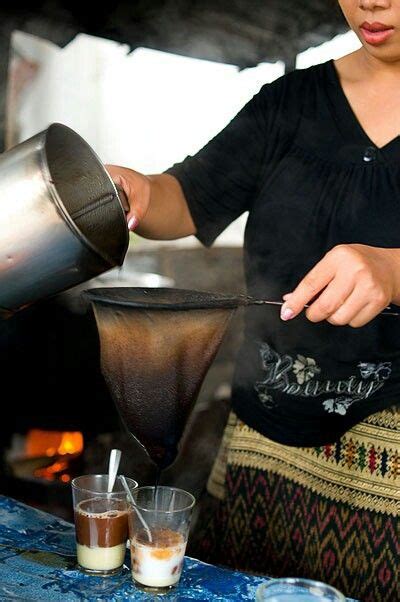 A Woman Pouring Something Into A Pot On Top Of A Table Next To Cups And