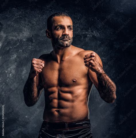 Professional Muay Thai Boxer With Naked Torso Posing For A Camera Studio Photo Against A Dark