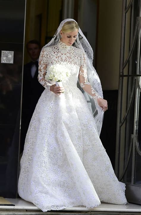 A Woman In A Wedding Dress Is Walking Out Of The Church With Her Veil Pulled Back