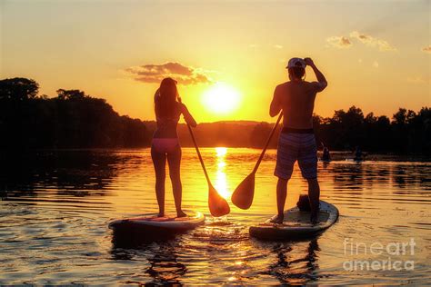 A Silhouette Of A Couple On A Stand Up Paddle Boards Sup At Sunset On