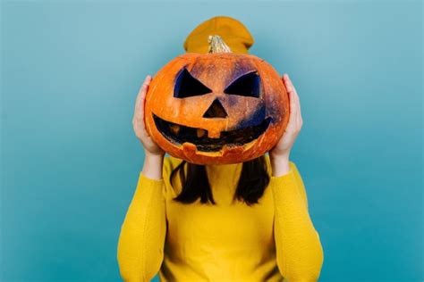 Premium Photo Woman Hiding Her Face Behind Carved Spooky Pumpkin