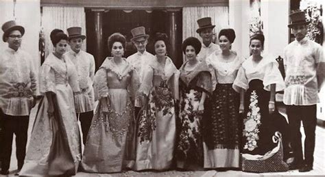 A Group Of People Standing Next To Each Other In Front Of A Door Wearing Dresses And Hats