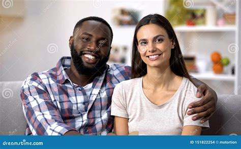 Smiling Multiracial Couple Hugging And Looking To Camera Social