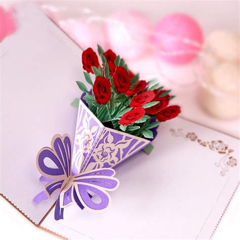 A Bouquet Of Red Roses Sitting On Top Of An Open Card With A Butterfly