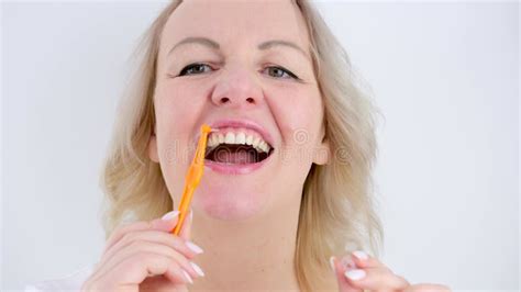 Middle Aged Blonde Woman Enjoys Between A Toothbrush Brushing Teeth Brushing Dirt Taking Care Of