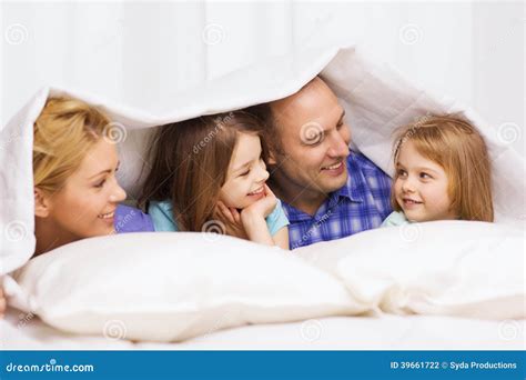 Familia Feliz Con Dos Niños Debajo De La Manta En Casa Foto de archivo