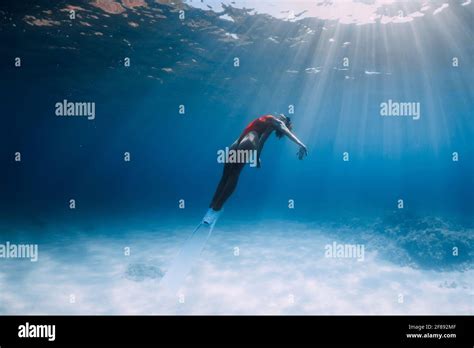 Woman Freediver In Swimsuit With Fins Glides Underwater Over Sand In