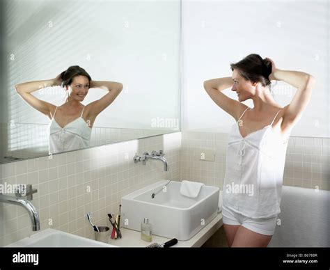 Woman In Bathroom Looking In The Mirror Stock Photo Alamy