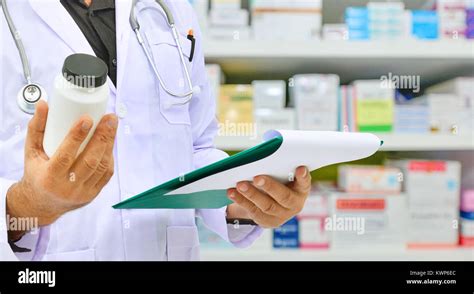 Pharmacist Holding Medicine Bottle And Prescription Chart For Filling