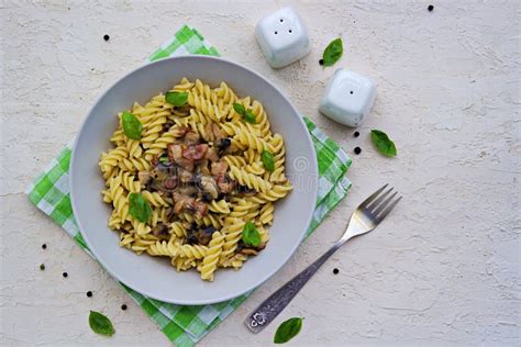 Fusilli Pasta With Mushrooms Bacon And Green Basil In A Gray Bowl On A