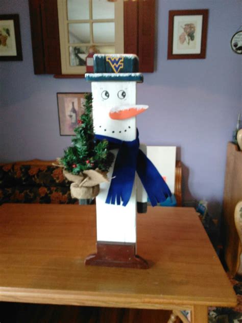 A Paper Snowman Sitting On Top Of A Wooden Table