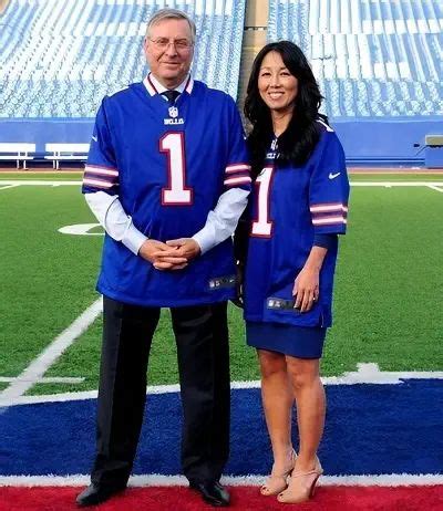 A Man And Woman Standing Next To Each Other In Front Of A Football