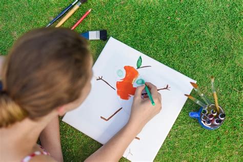 Mujer joven artista e ilustradora dibujando con un lápiz en un césped