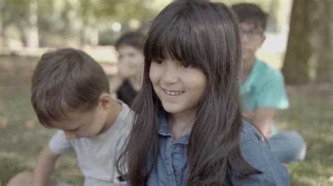 Vídeo de arquivo Gratuito Linda garota latina sentada na grama do parque amigos